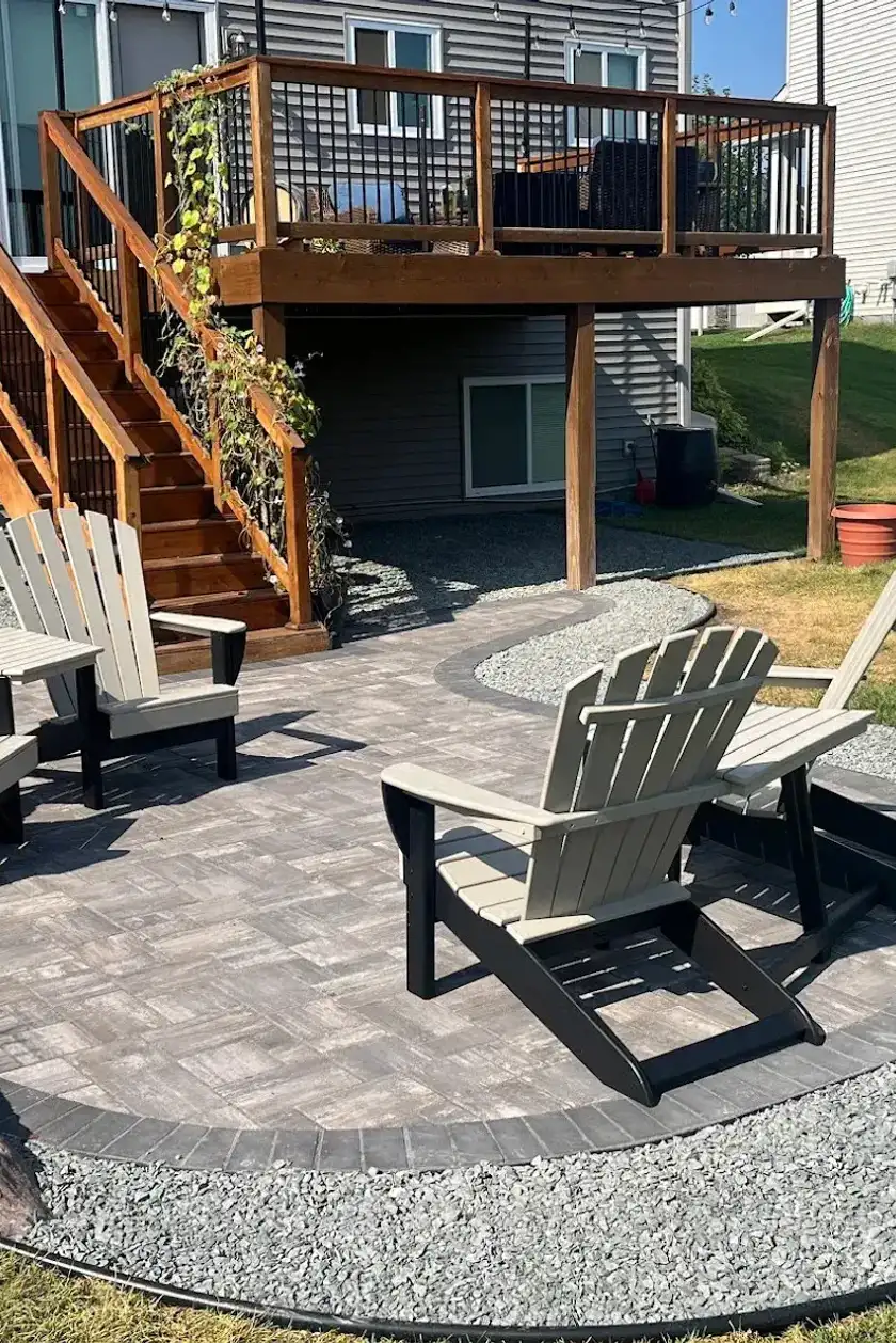 Beautiful curved paving stone patio with a block retaining wall and decorative rock bed in Edmonton.